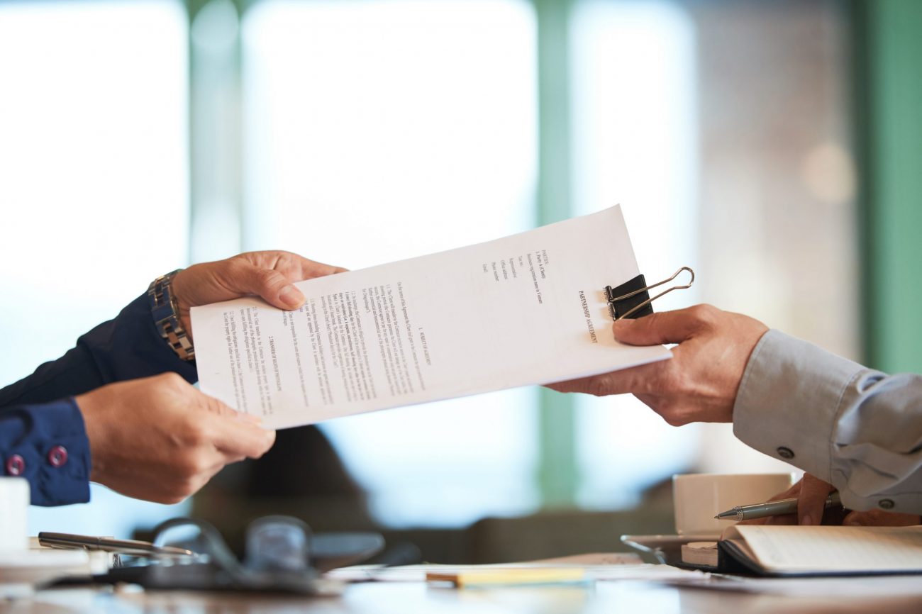Partnership Man being handed documents illustrates blog "What Is a Restraining Order?"