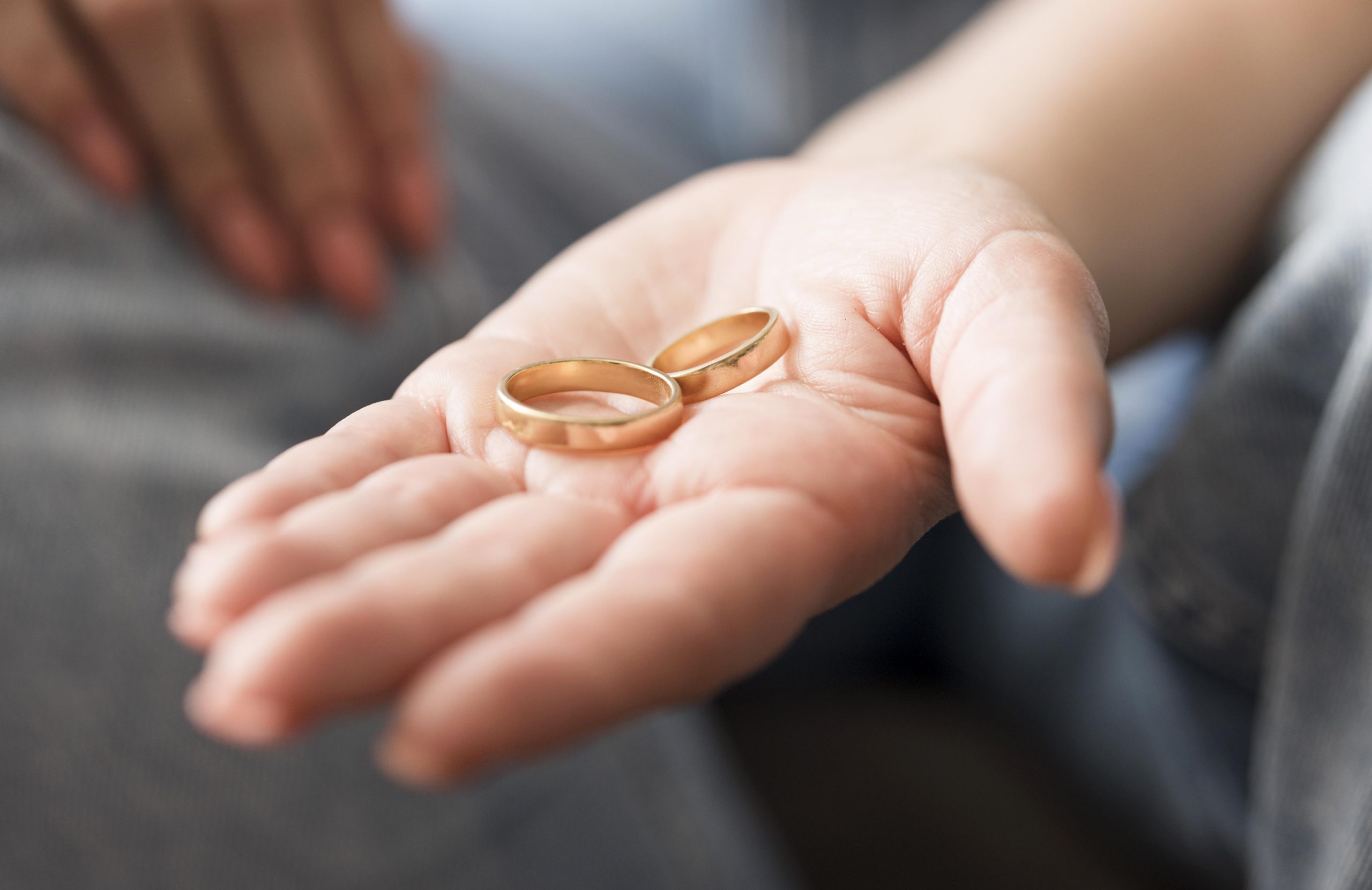 Closeup of woman with wedding rings on the palm of her hand illustrates blog "Can I Use the Restraining Order To Get Divorced?"