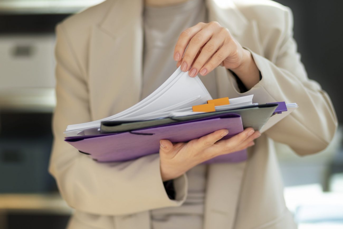 form-fp Closeup of woman holding stack of folders and papers illustrates blog "What Are the Requirements for a Restraining Order in California?"