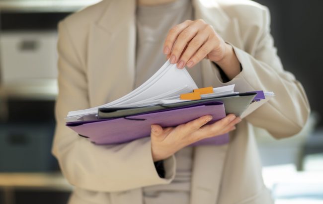 form-fp Closeup of woman holding stack of folders and papers illustrates blog "What Are the Requirements for a Restraining Order in California?"