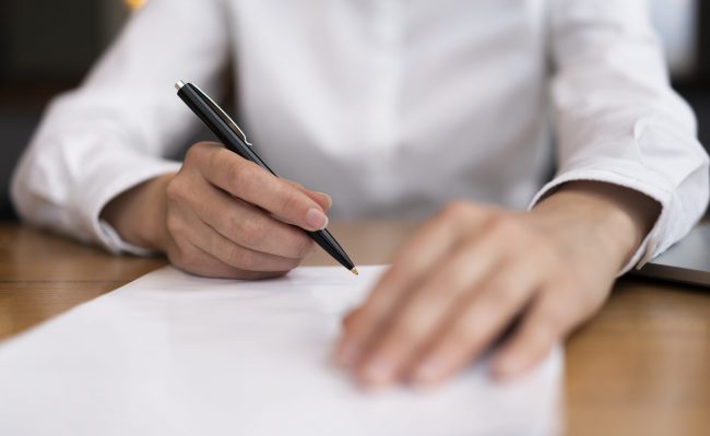 signing-fp Closeup of person signing papers illustrates blog "What Is the Difference Between a Protective Order and a Restraining Order in California?"