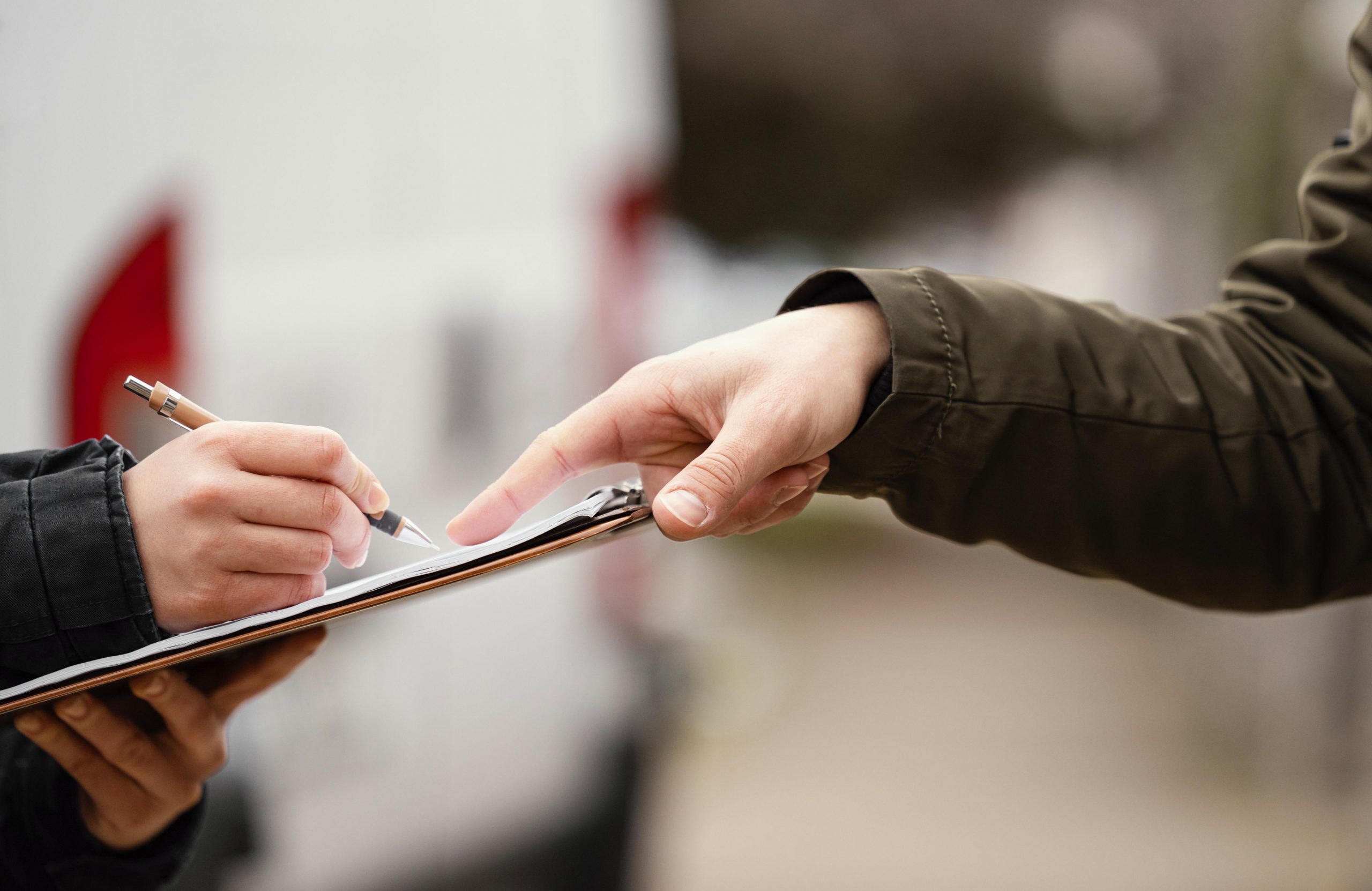 Hand pointing as person signs on clipboard.
