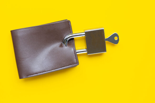 Wallet with padlock and key on yellow background.